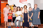 Gruppe von Kindern und eine erwachsene Person mit Urkunden bei einer Preisverleihung. Im Hintergrund ein Werbebanner.