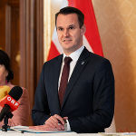 Bildbeschreibung: Ein Mann spricht in eine Mikrofoneinrichtung.