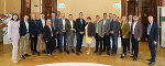 Gruppe von Menschen in formeller Kleidung posiert in einem Innenraum mit klassischer Architektur.