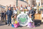Bildbeschreibung: Gruppe von Menschen bei einer Veranstaltung im Freien mit einem großen Steiermark Frühling-Logo.