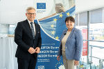Bildbeschreibung: Eine Frau und ein Mann stehen vor einem Banner mit der Europaflagge.