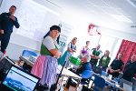Person in Tracht hält Vortrag vor Publikum im Konferenzraum.